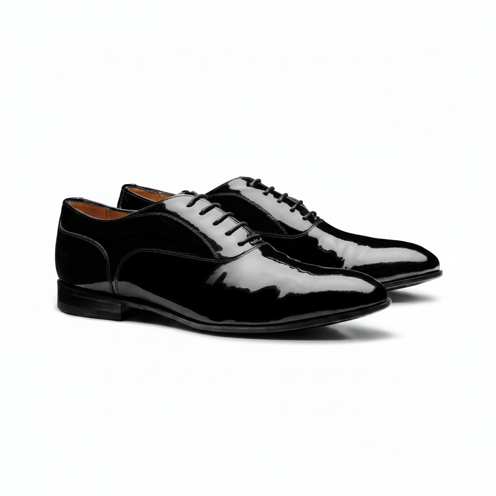 Pair of black patent leather shoes on a white background